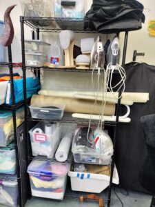 Shelves containing ironing materials, including irons, sleeve boards, hams, and interfacing