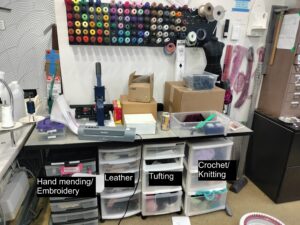 Picture of textiles area, showing four shelving units under a desk labelled.