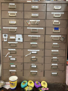 Shows brown metal drawers on top of two larger shelves. Shelves are labelled.